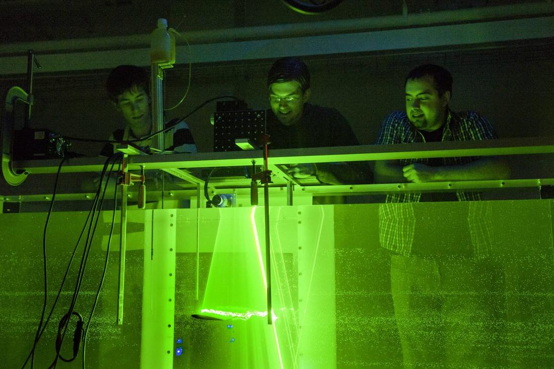 学生们在科学实验室里俯瞰着一个绿色的发光盒子. 点击此处了解更多获得成功的机会.